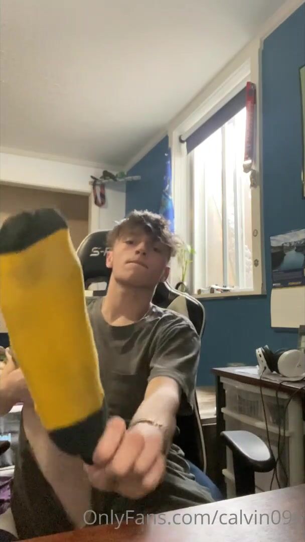 Rubio joven huele calcetines y enseña pies