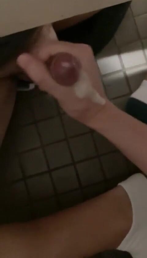Twink jerks uncut cock under stall